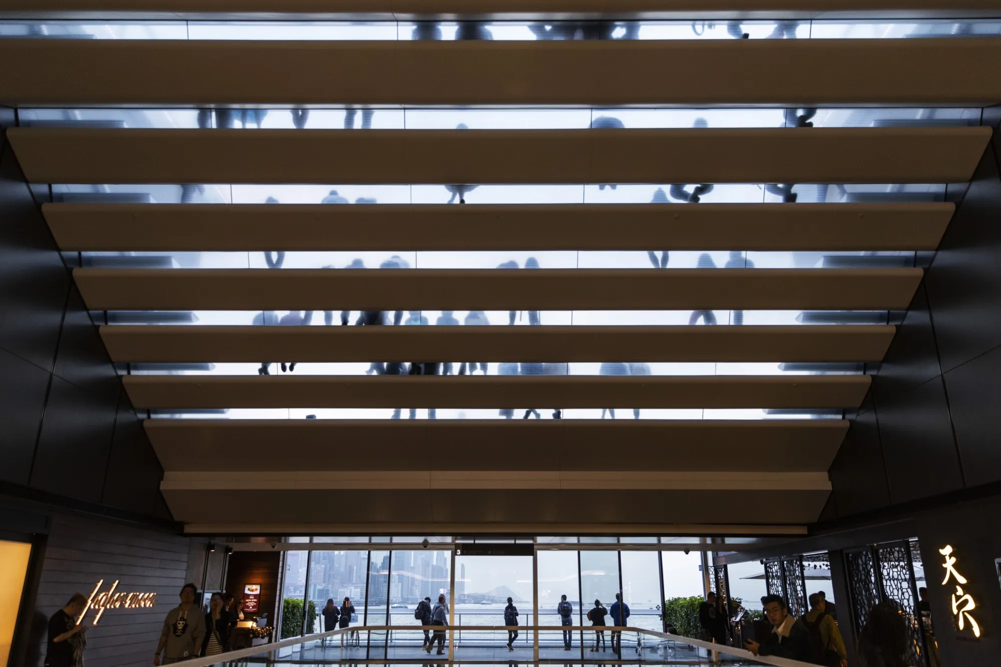 People sit on steps of Ocean Terminal Deck at Harbour City shopping mall in Hong Kong.
