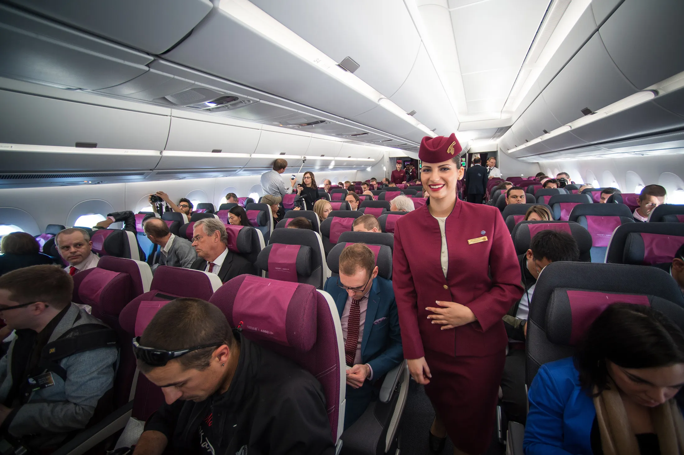 A Qatar Airways flight attendant smiles during a flight in an Airbus A350 over Toulouse, southwestern France.
