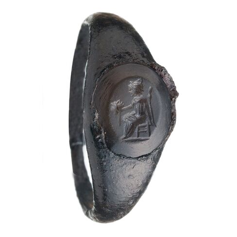 A beautiful first century signet ring, an onyx set in a beveled iron ring; the engraving shows the muse of comedy, Thalia, holding a mask.