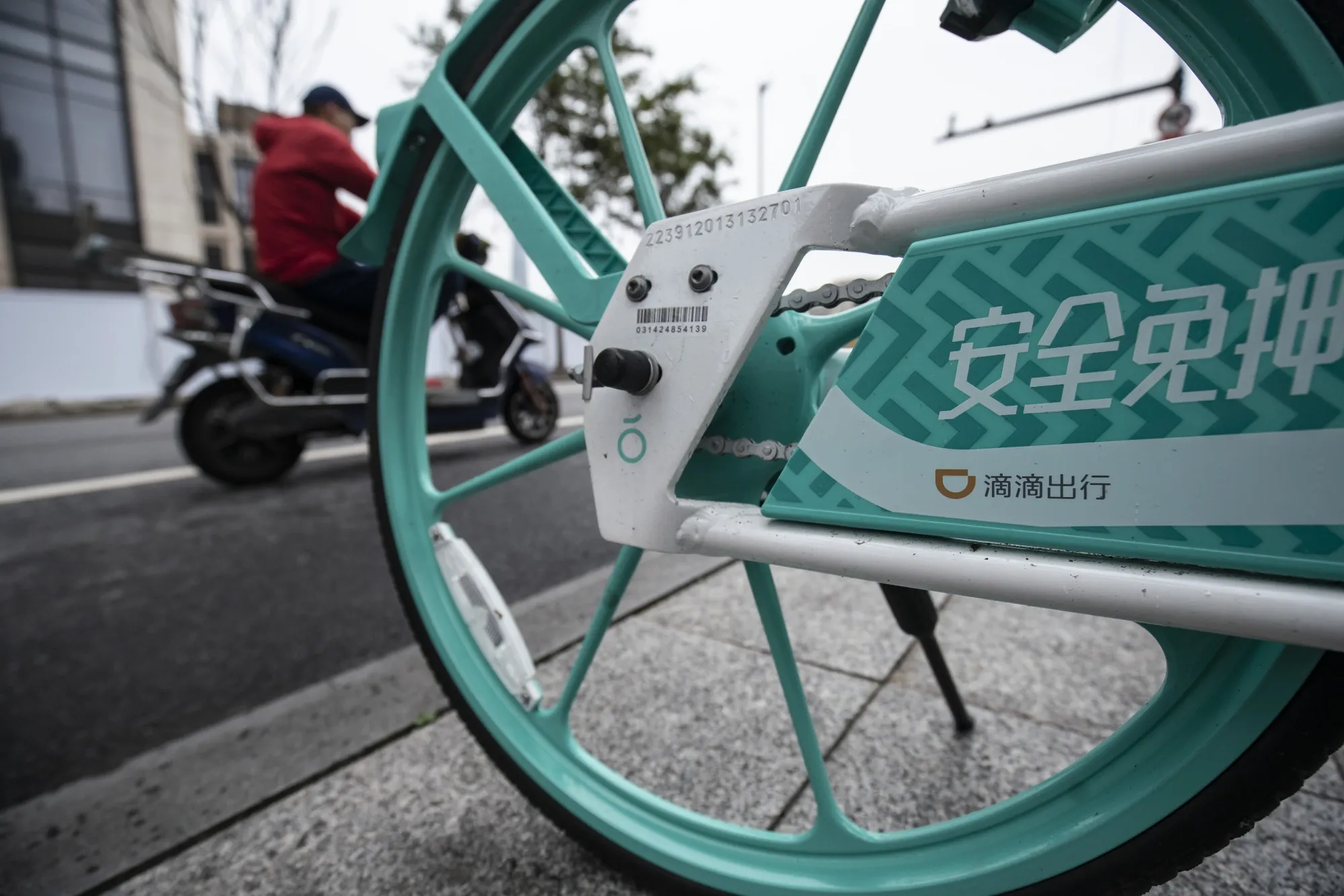 The logo of Didi Chuxing Inc. on a shared-bike standing on the sidewalk in Shanghai.