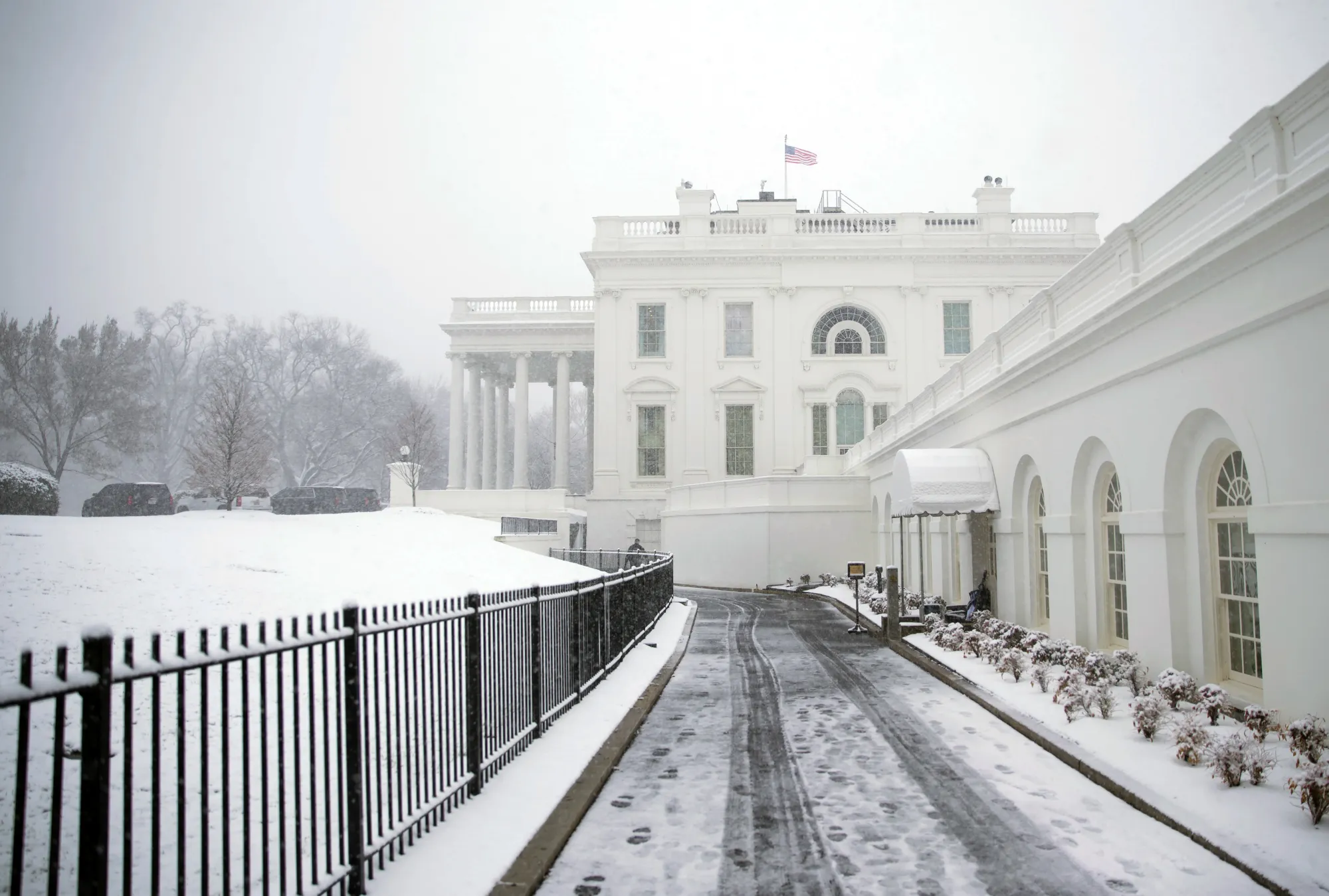 An American flag flies outside the White House during a snow storm in Washington, D.C., U.S., on Wednesday, March 21, 2018.