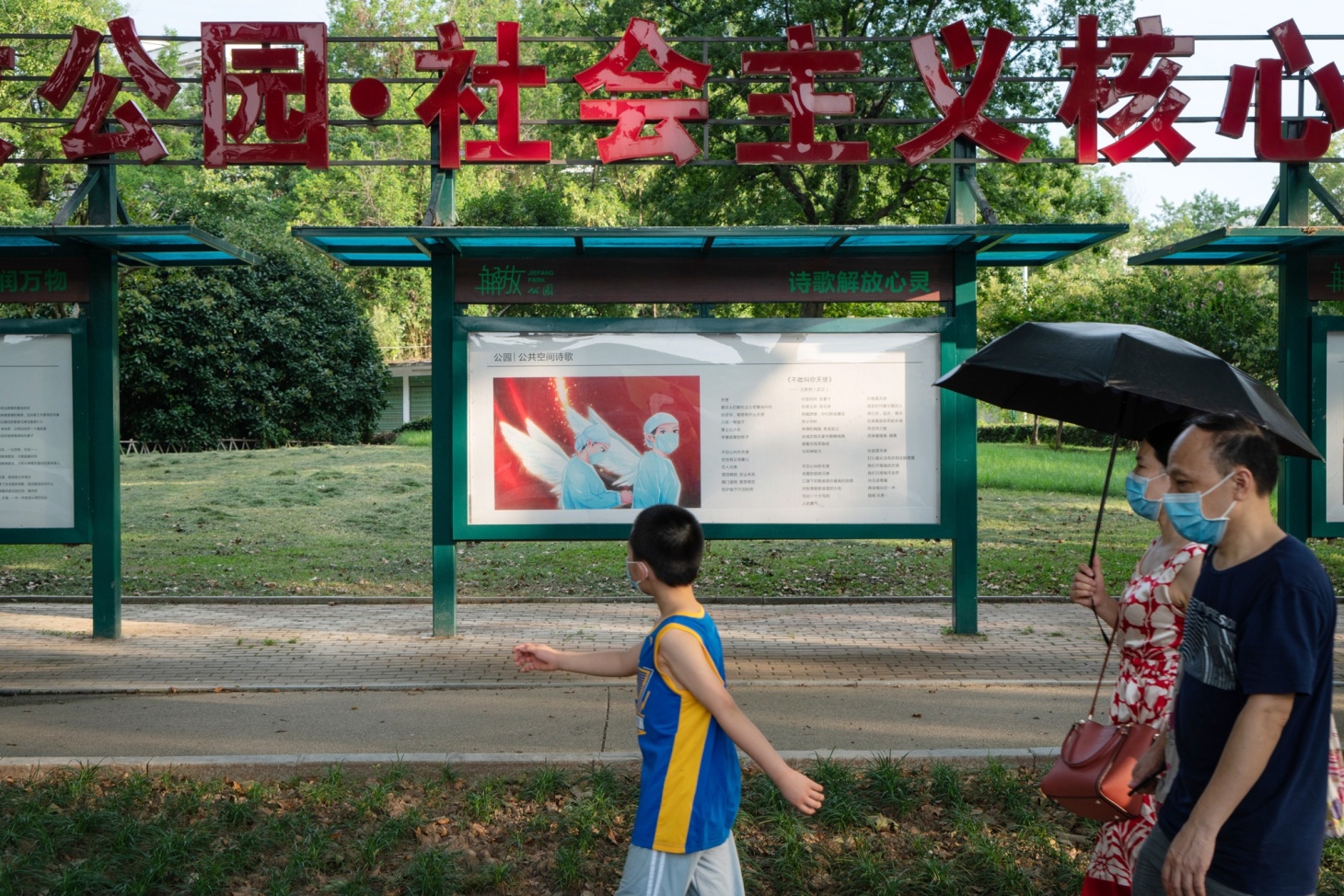 A family walk past a poem on display at Jiefang Park, a tribute to health-care workers, in Wuhan.