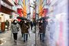 Pedestrians wearing protective masks and holding umbrellas walk in the Akihabara shopping district of Tokyo, Japan.