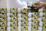 An employee arranges genuine bundles of South Korean 50,000 won banknotes for a photograph at the Counterfeit Notes Response Center of KEB Hana Bank in Seoul, South Korea, on Monday, Aug. 14, 2017.