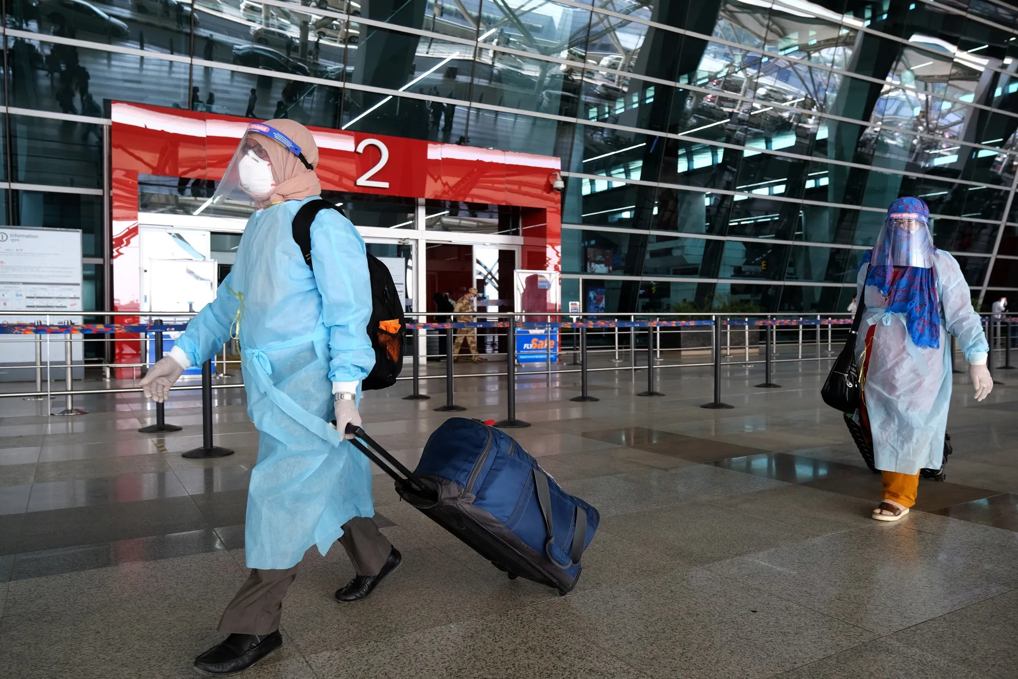 Travelers wearing personal protective equipment (PPE) walk through the Indira Gandhi International Airport&nbsp;in New Delhi, India, on&nbsp;May 25.