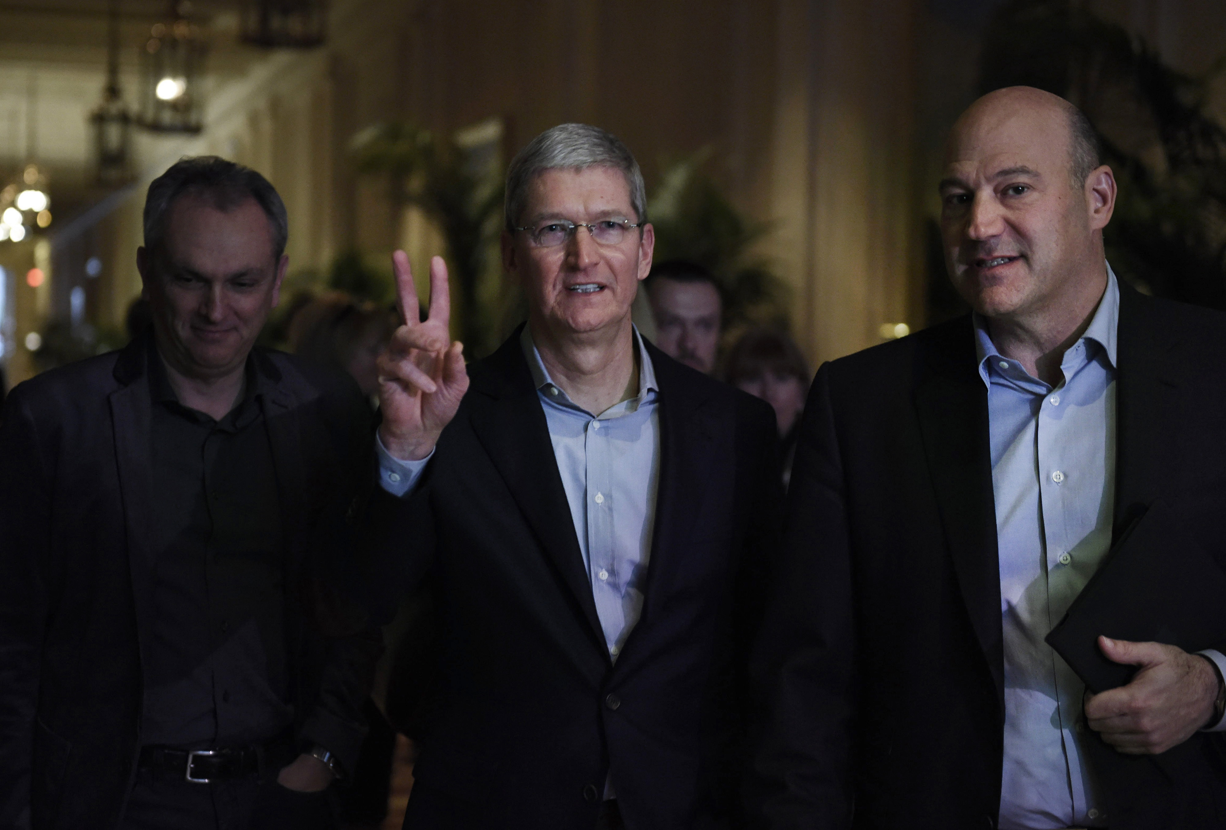Tim Cook, chief executive officer of Apple Inc., center, arrives to speak with Gary Cohn, president and chief operating officer of Goldman Sachs Group Inc., right, at the Goldman Sachs Technology And Internet Conference in San Francisco, California, U.S., on Tuesday, Feb. 10, 2015.
