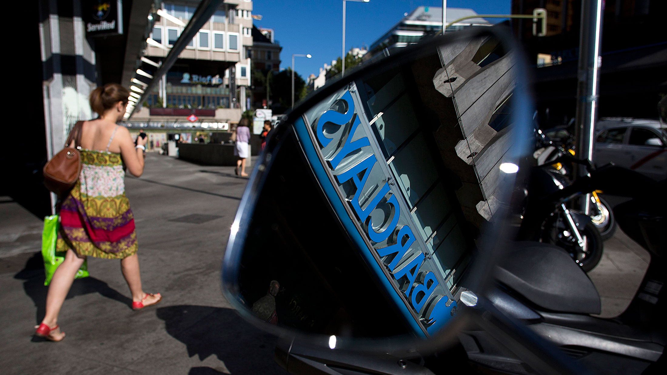 A Barclays logo is seen in the wing mirror of a scooter parked outside a Barclays Plc bank branch in Madrid.
