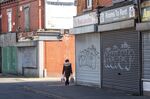 A woman passes closed stores in Leeds, U.K.