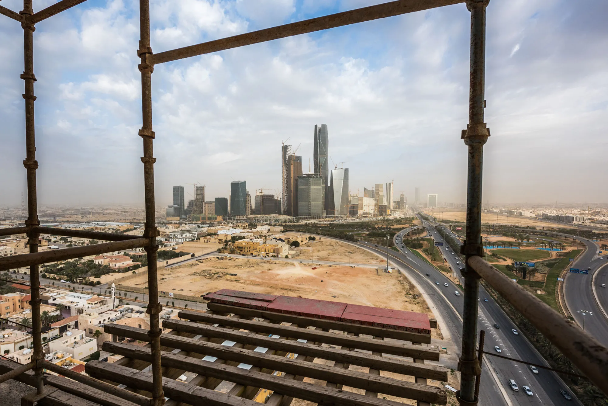 The King Abdullah financial district sits on the horizon seen from a skyscraper under construction in Riyadh, Saudi Arabia, on Sunday, Jan. 10, 2016. Saudi Arabian stocks led Gulf Arab markets lower after oil extended its slump from the lowest close since 2004.
