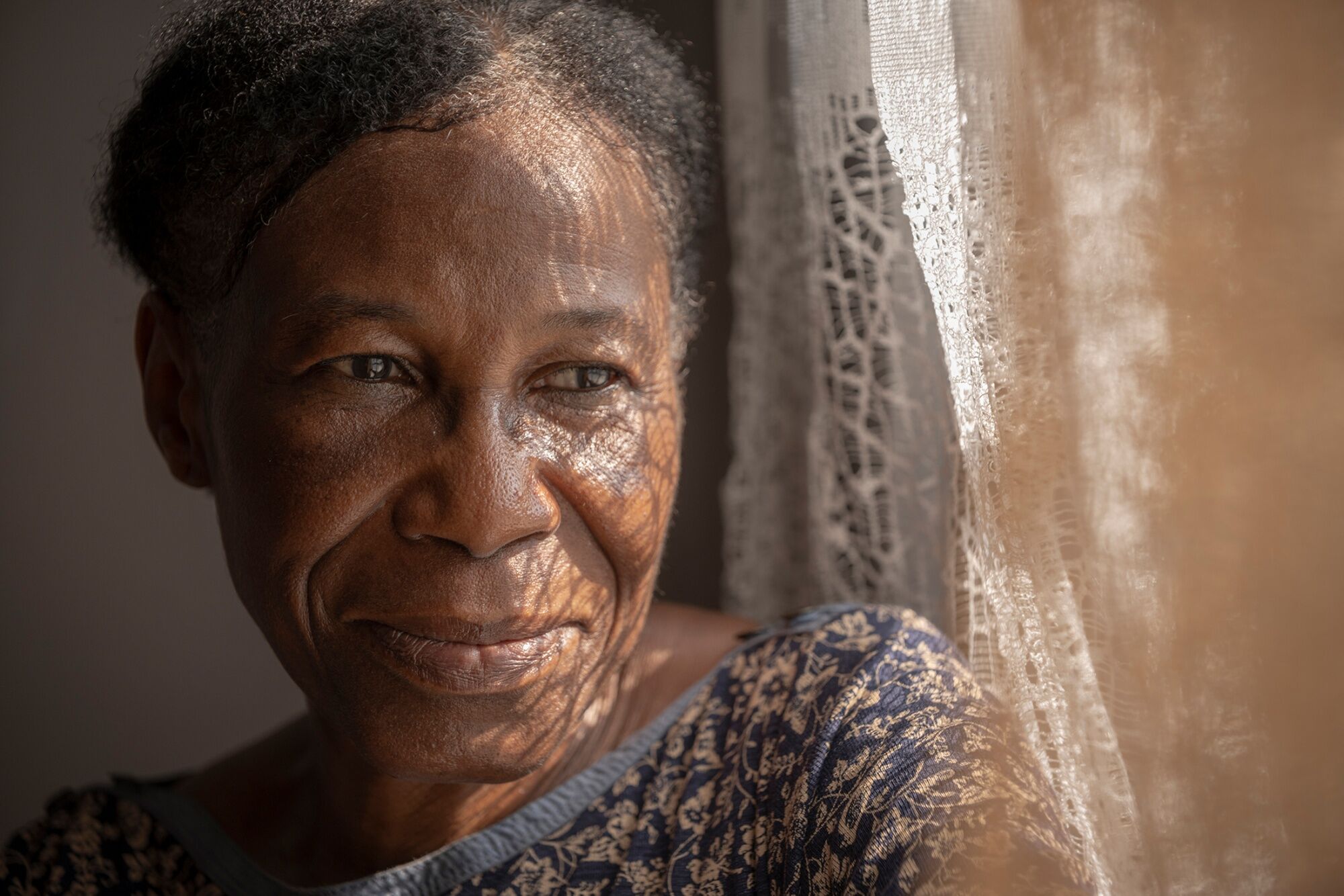 Portrait of Margaret Edison looking out a window, highlighting her advocacy for family planning and education in Nigeria.