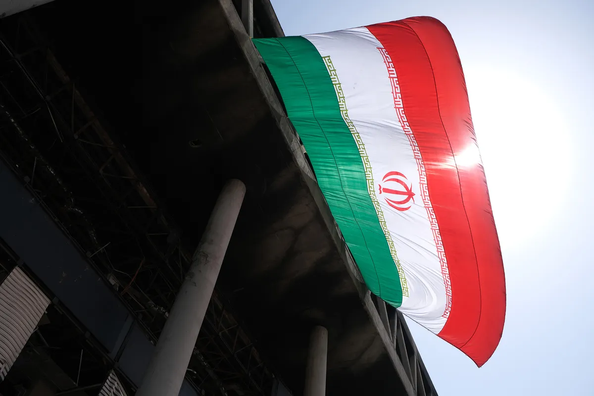 پرچم ملی جمهوری اسلامی ایران بر دیوار ساختمان شیشه‌ای که در تاریخ ۲۵ ژوئن در تهران، ایران، مورد حمله موشکی اسرائیل قرار گرفت.