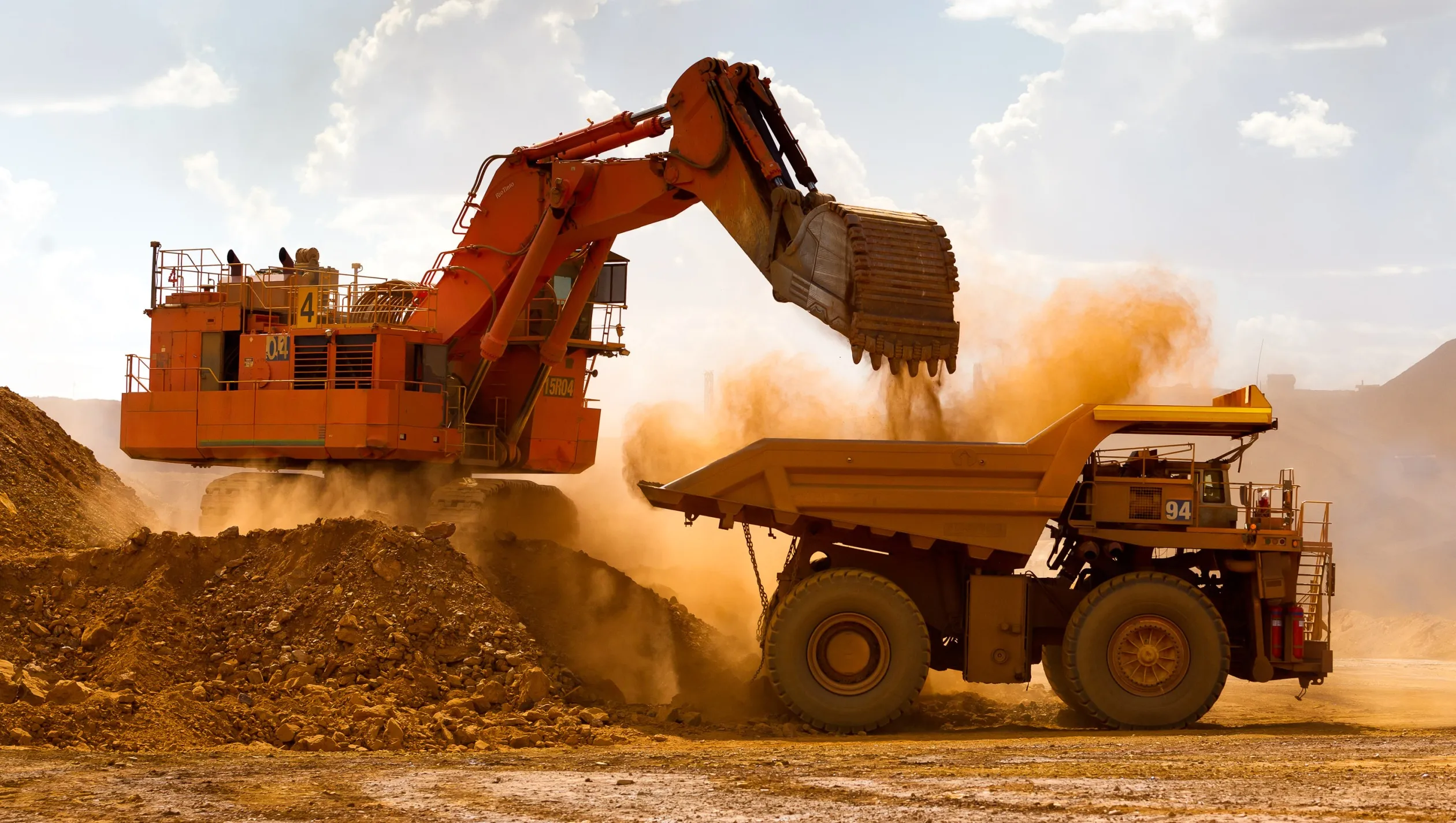 A haul truck is loaded by a digger with material from an iron ore mine.