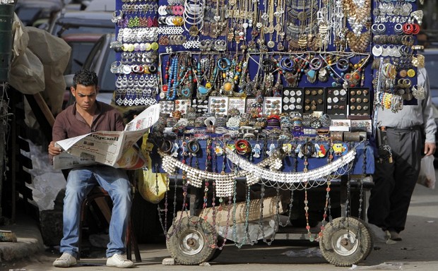 An Egyptian street vendor reads a newspaper while waiting for customers in downtown Cairo, Egypt