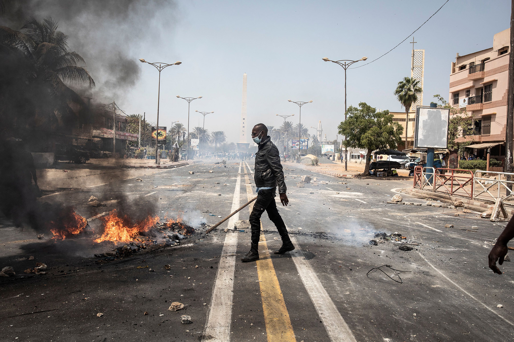 A police officer clears away a fire after violent protests broke out in Dakar, March 3.
