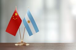 Argentinian And Chinese Flag Pair On A Desk Over Defocused Background