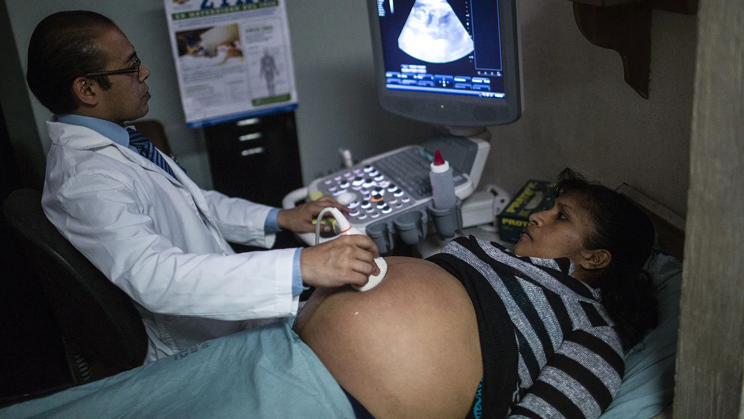 A poster with information about the Zika virus hangs on a wall as a pregnant woman undergoes an ultrasound treatment at the Social Security Institute maternity ward in Guatemala City, Guatemala, on Feb. 2, 2016.
