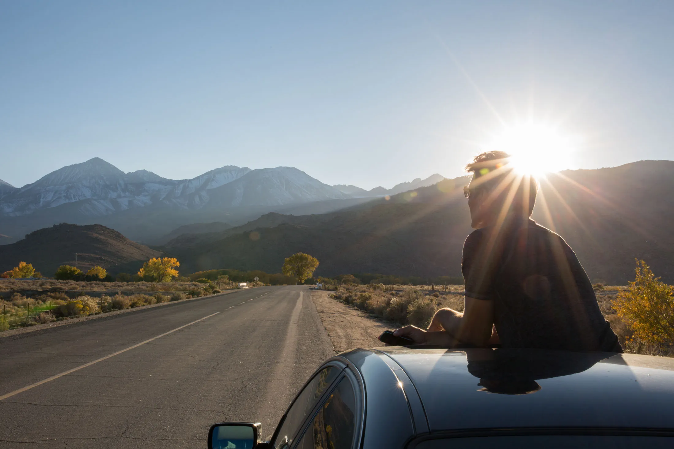 Man looks out across desert highway from sunroof