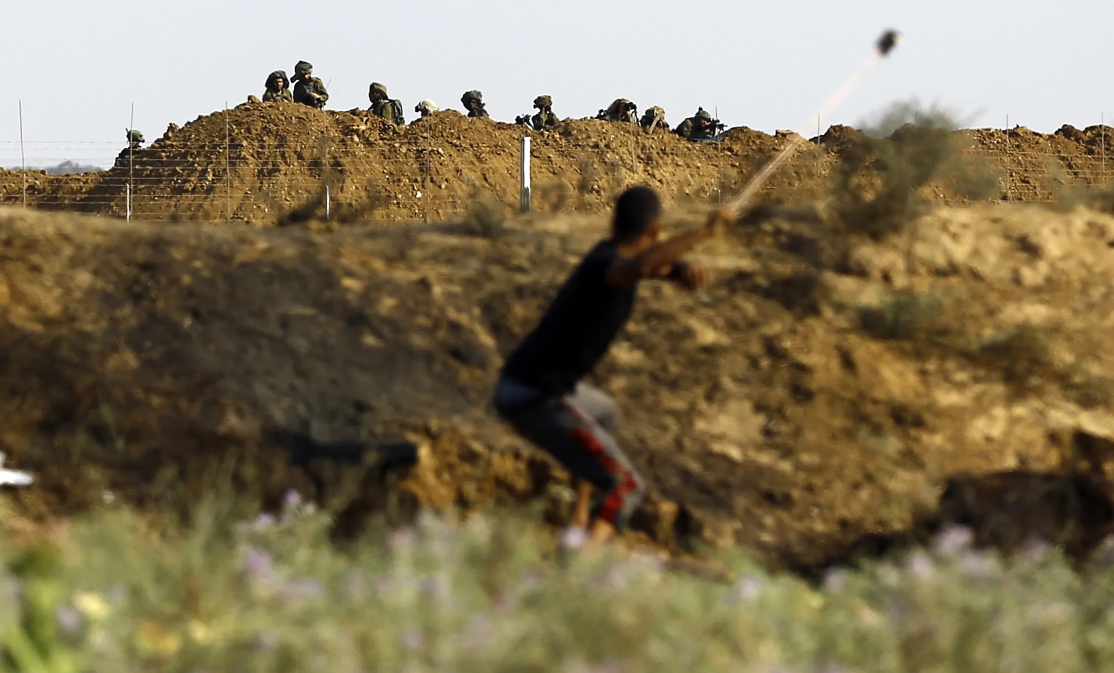 A Palestinian protester uses a sling to hurl a stone towards Israeli troops during clashes with Israeli security forces near the border fence east of Jabalia refugee camp in the Gaza strip on July 21, 2017.
