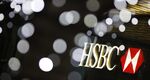 Signage for HSBC shines through decorative lights outside the HSBC tower in Canary Wharf business district in London, U.K., on Saturday February 13, 2016.
