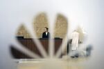 An employee is seen through a window displaying the Huawei Technologies Co. logo.