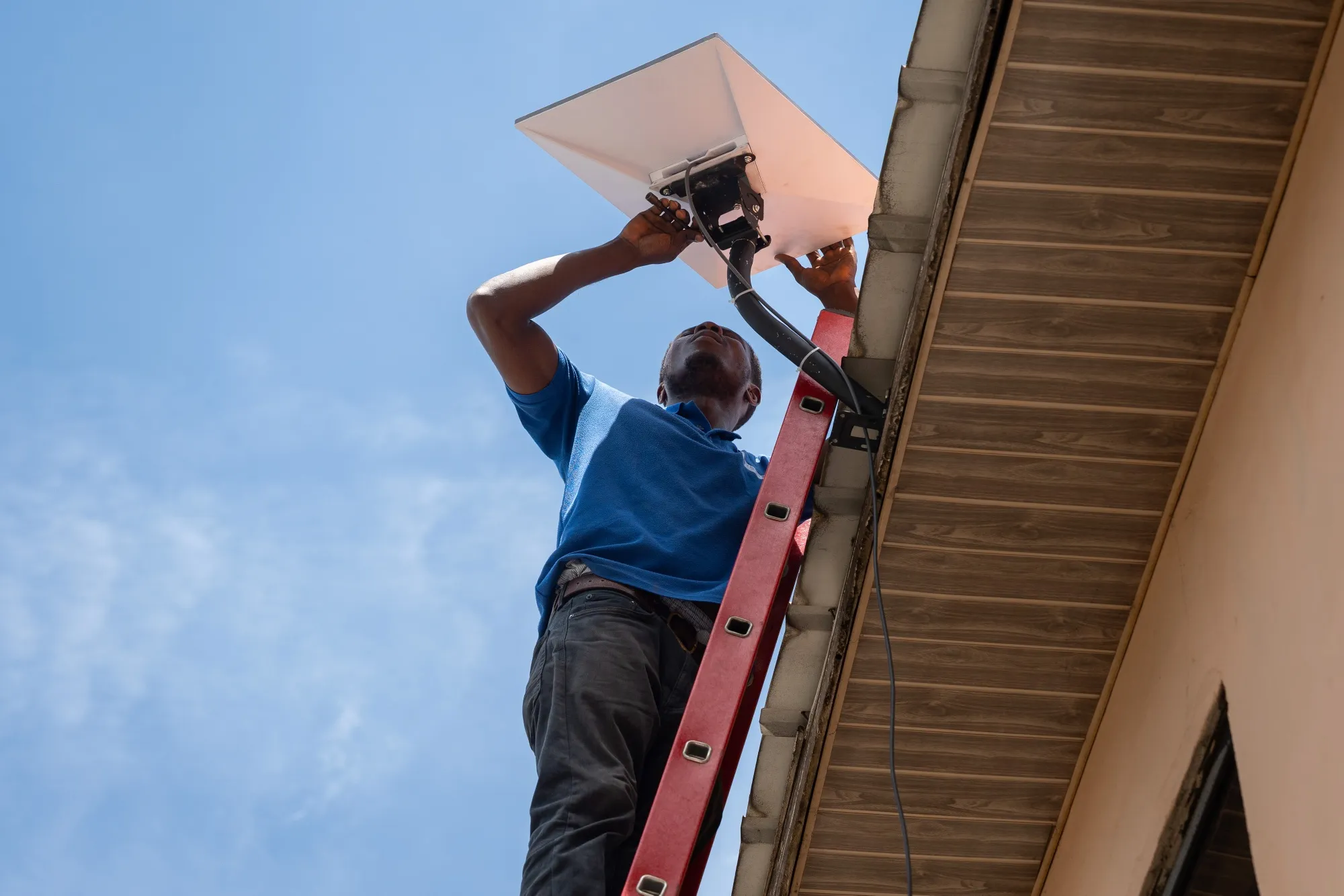 A technician installs a Starlink satellite-internet communication system antenna on the roof of a home in Accra.