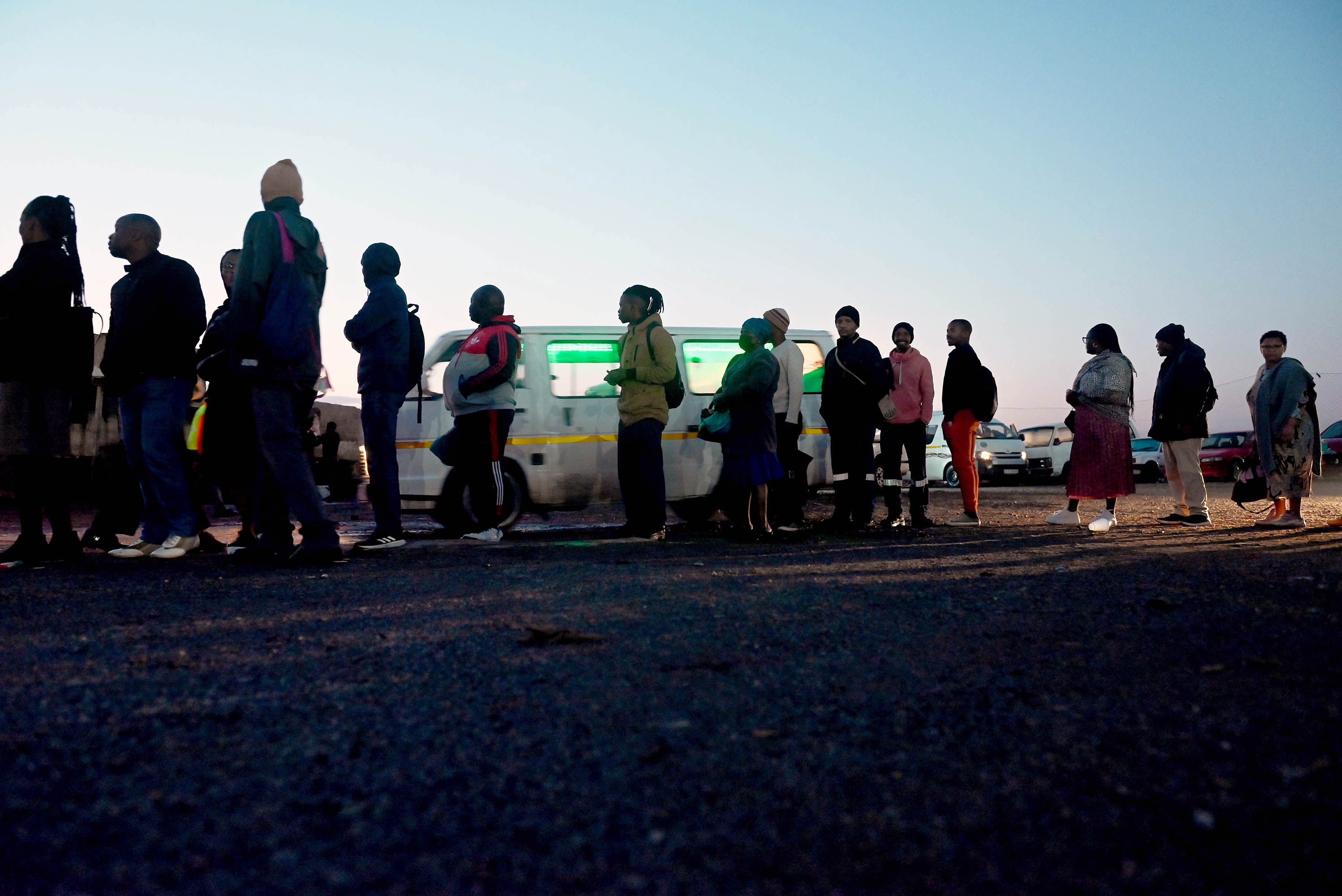 People line up on a chilly May morning to wait at a taxi stand in Katlehong