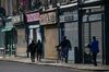 Pedestrians walk past shuttered businesses in London.