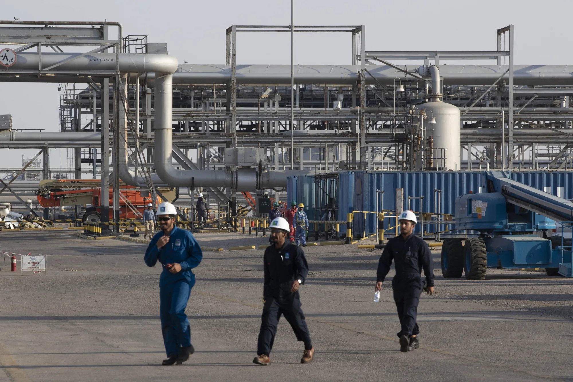 Workers pass oil transport pipes at Saudi Aramco's Abqaiq crude oil processing plant following a drone attack in Abqaiq, on Sept. 20.