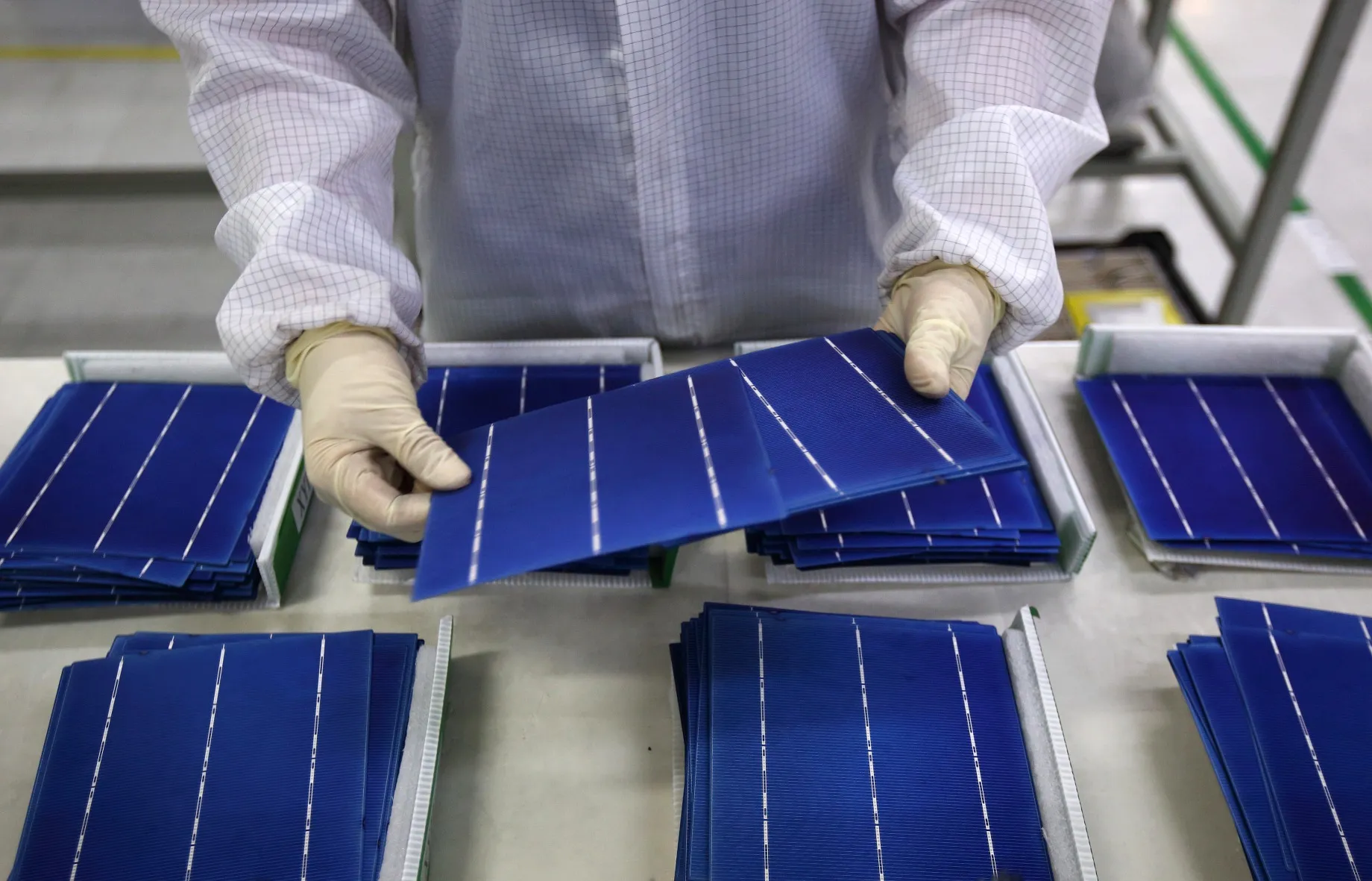 An employee performs a final inspection on solar cells on the production line at the Trina Solar factory in Changzhou, China.