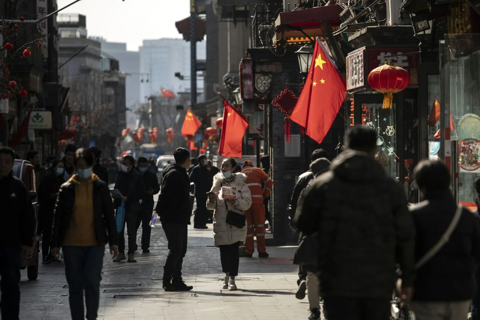 Pedestrians pass Chinese flags in Beijing.