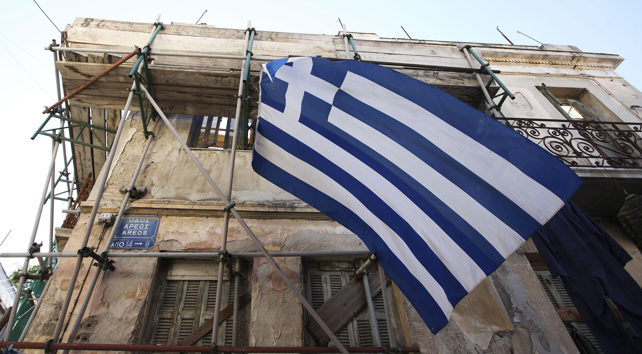 A Greek national flag flies from scaffolding outside an old building in the Plaka district of Athens, Greece, on Thursday, June 14, 2012. Greeks head to the ballot box in two days for a contest that may determine the fate of the world's first democracy and the future of the newest reserve currency, while roiling markets from Wellington to Wall Street.
