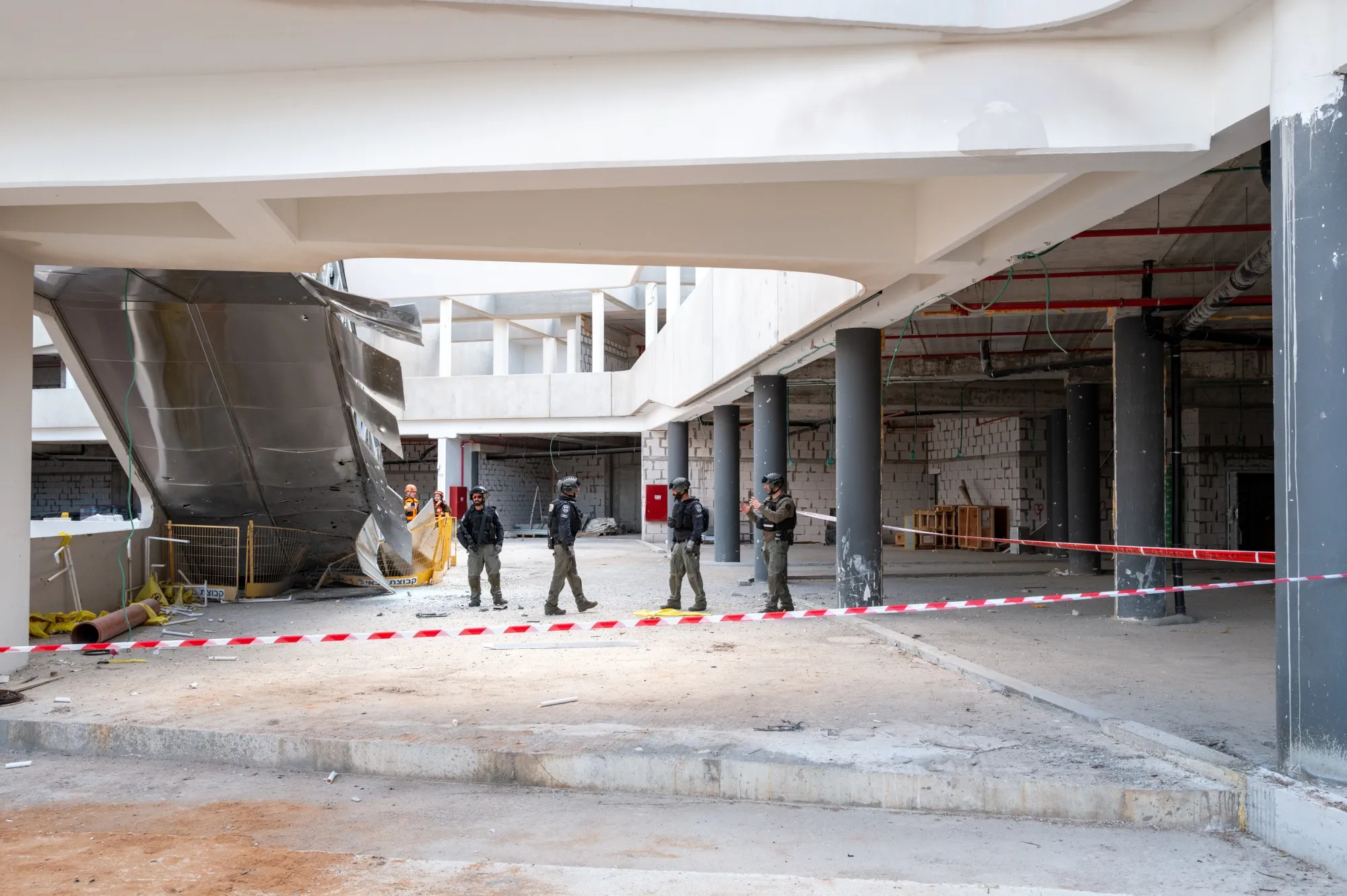 Israeli Home Front Command rescue and emergency personnel operate at the site of a missile, carrying a cluster munition warhead, struck a construction site, in Yehud, Israel.