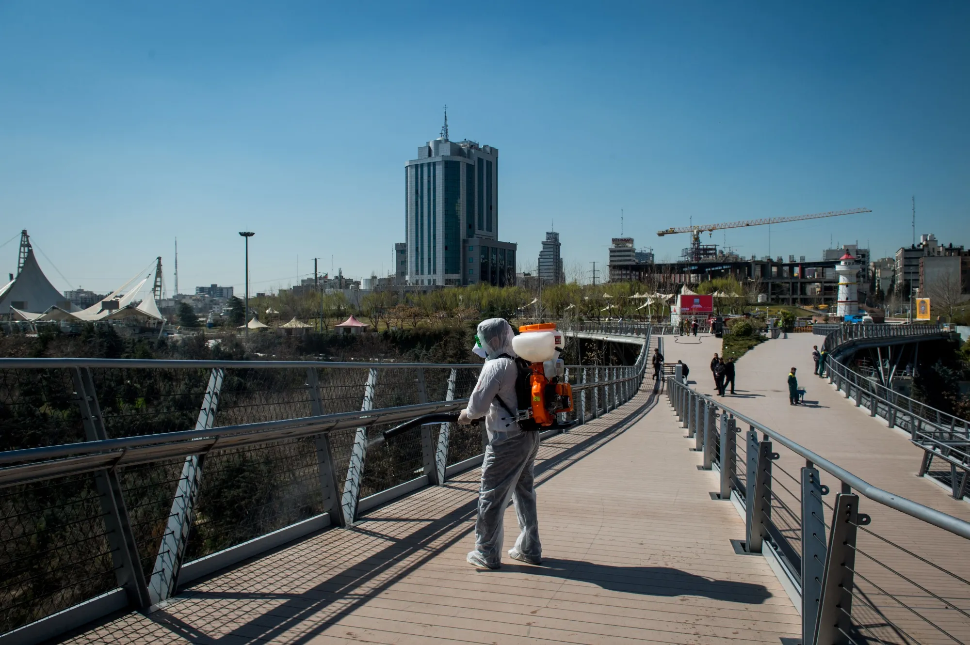 A firefighter wearing protective clothing sprays disinfectant on Tabia't bridge pedestrian overpass in Tehran, Iran, on March 9.