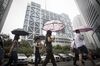 Pedestrians carrying umbrellas walk past the Shanghai Stock Exchange building in Shanghai, China, on Tuesday, Sept. 22, 2015. U.K. Chancellor of the Exchequer George Osborne is seeking to strengthen Britain's ties with China, including a possible stock-exchange link, as he underlines the country's value as an investment partner in spite of recent market shocks.
