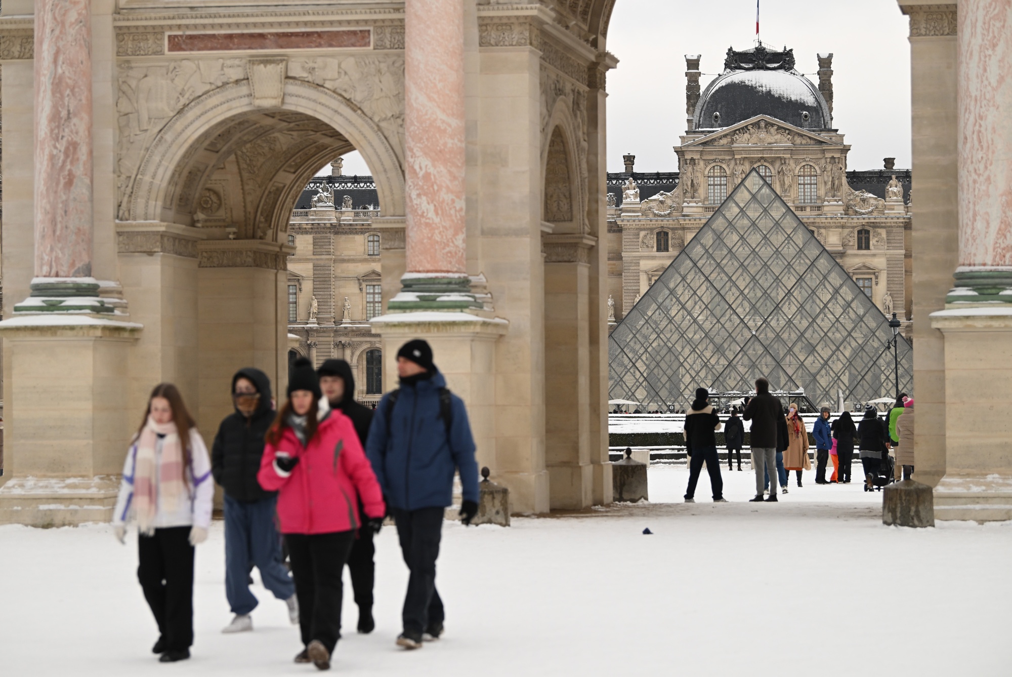 Visitors in the snow near the Louvre Museum pyramid during cold weather in central Paris, France, on Wednesday, Jan. 7, 2026. Unseasonably cold conditions are set to persist for weeks in central and northern Europe, while major weather models have nudged colder around mid-January. Photographer: Benjamin Girette/Bloomberg