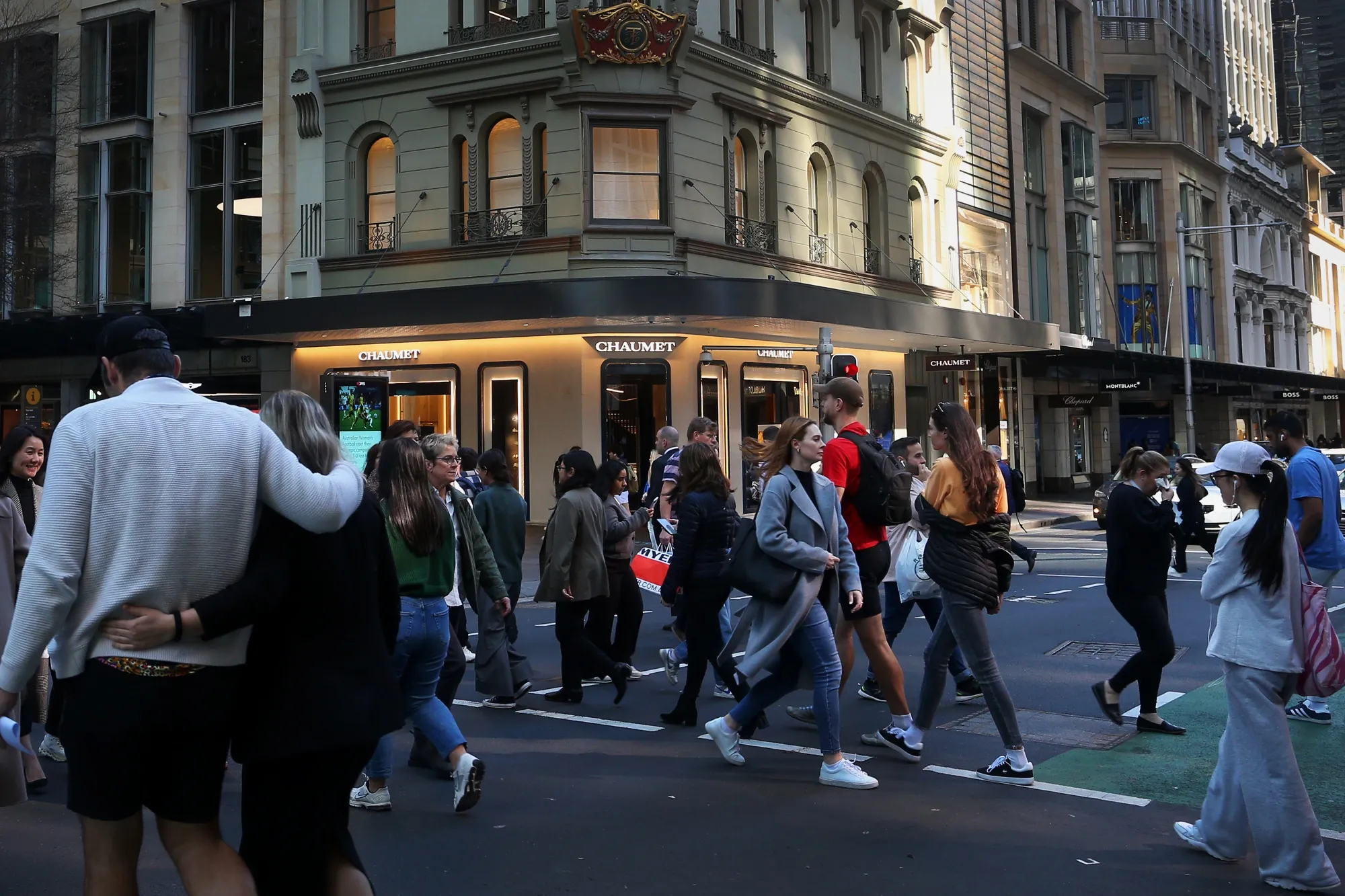 Pedestrians cross a street in the central business district in Sydney, Australia.