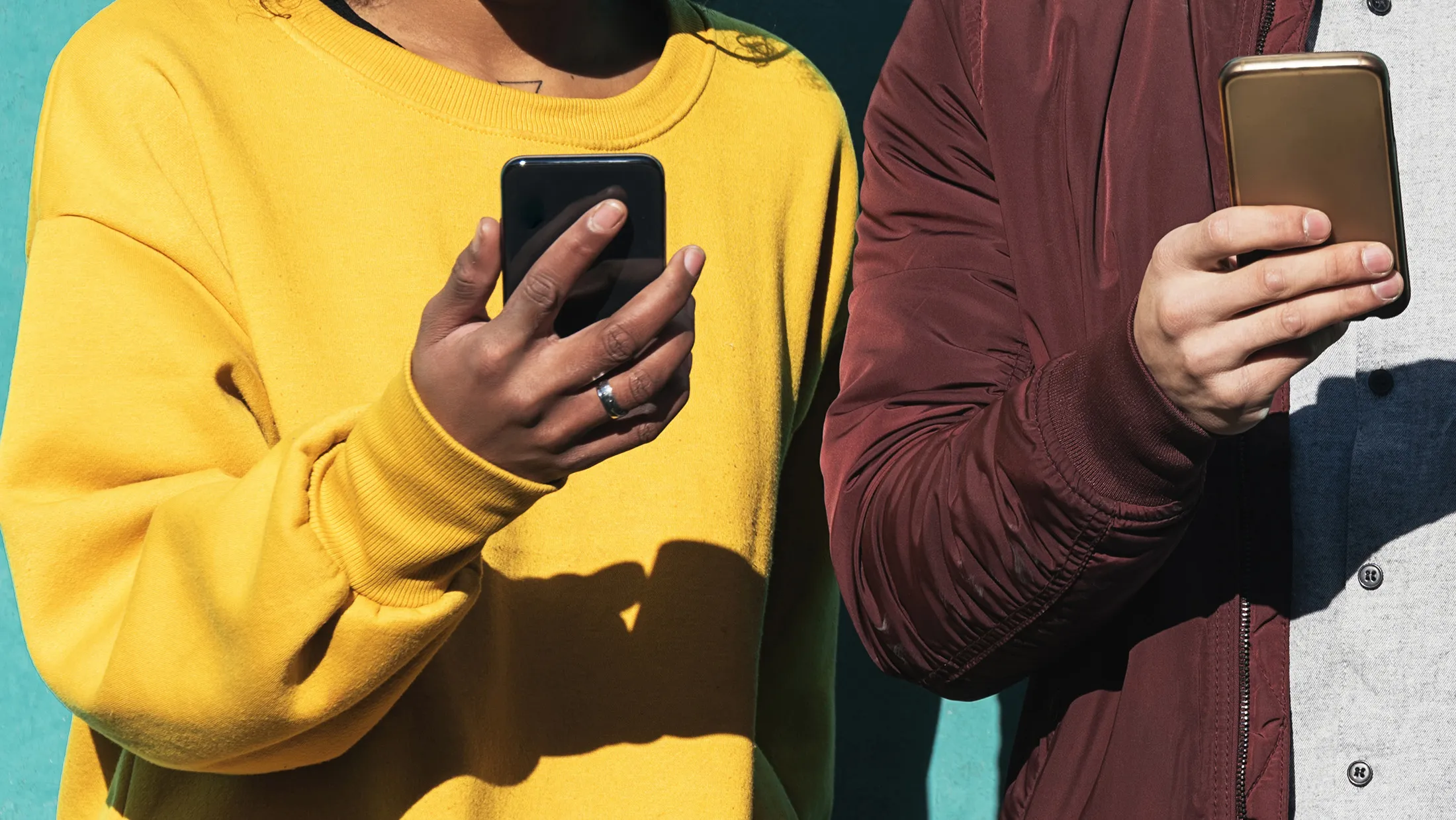 Two happy friends using the mobile in the street.