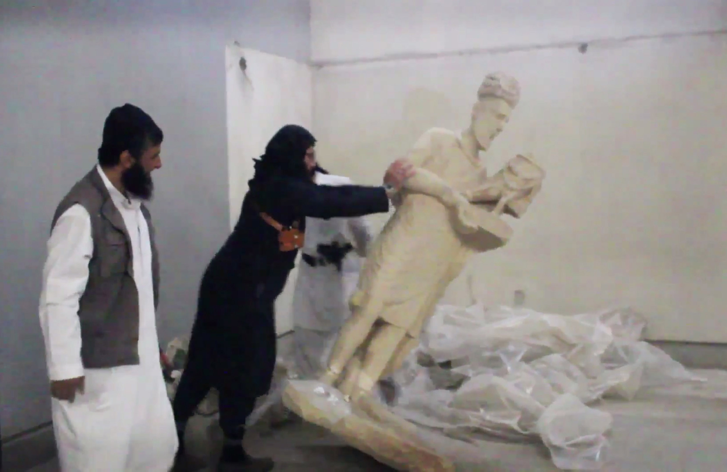 In this image made from video posted on a social media account affiliated with the Islamic State group on Feb. 26, 2015, which has been verified and is consistent with other AP reporting, a militant topples an ancient artifact in the Ninevah Museum in Mosul, Iraq. The extremist group has destroyed a number of shrines --including Muslim holy sites -- in order to eliminate what it views as heresy.
