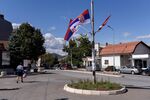 A resident walks past Serbian national flags displayed on a post in the town&nbsp;near Mitrovica, Kosovo, on Sept. 19.