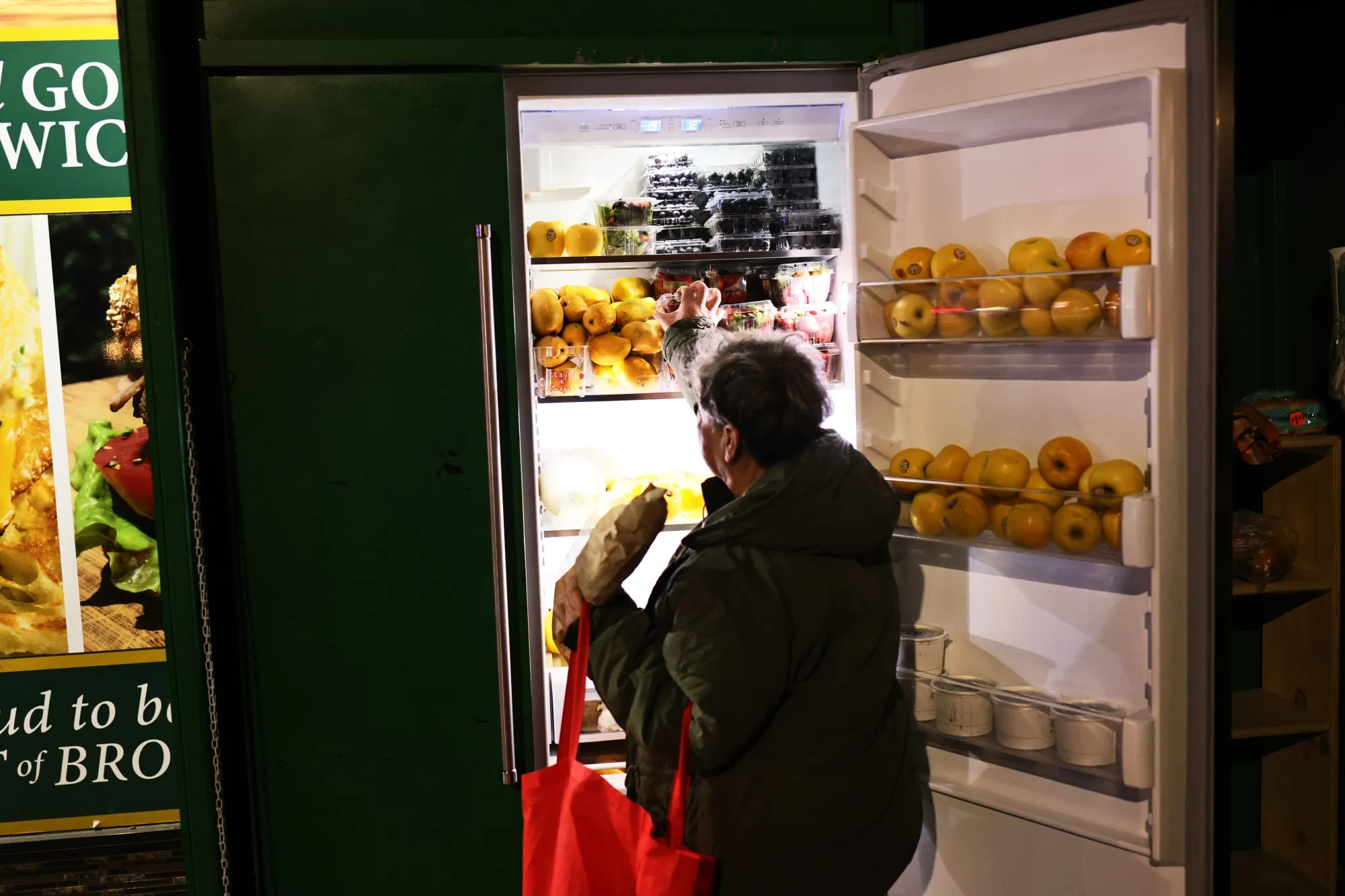A woman takes food from a mutual aid group's street refrigerator on March 2&nbsp;in the Fort Greene neighborhood of Brooklyn. One Love Community Fridge is one of many&nbsp;organizations that began as a response to the long lines at food banks that started when the coronavirus pandemic spread to New York.&nbsp;