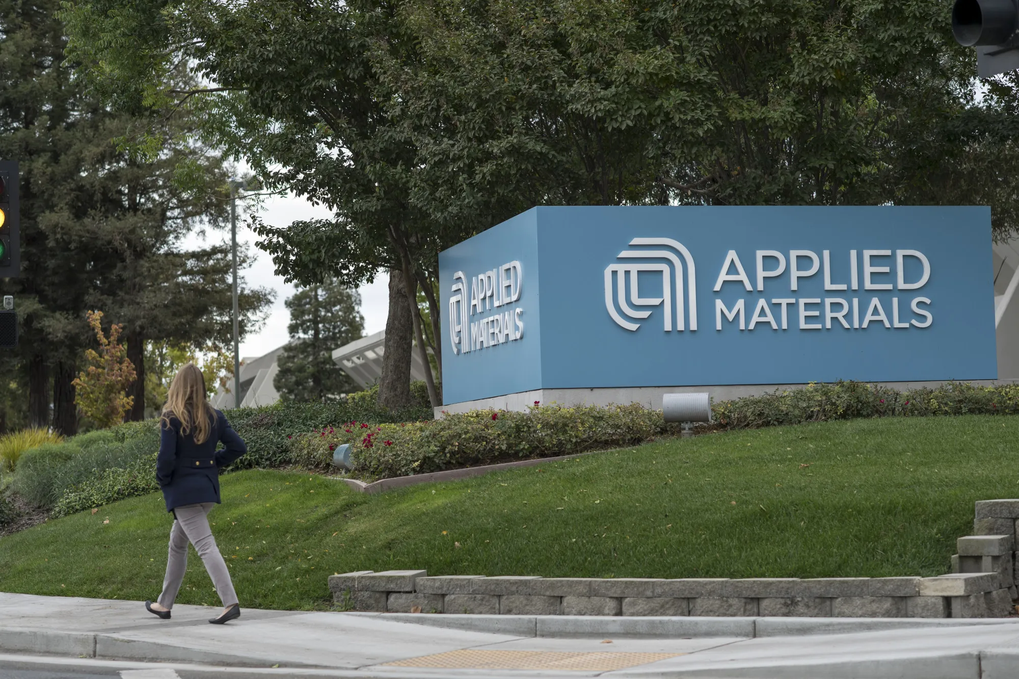 A pedestrian walks past the Applied Materials Inc. facility in Santa Clara, California.