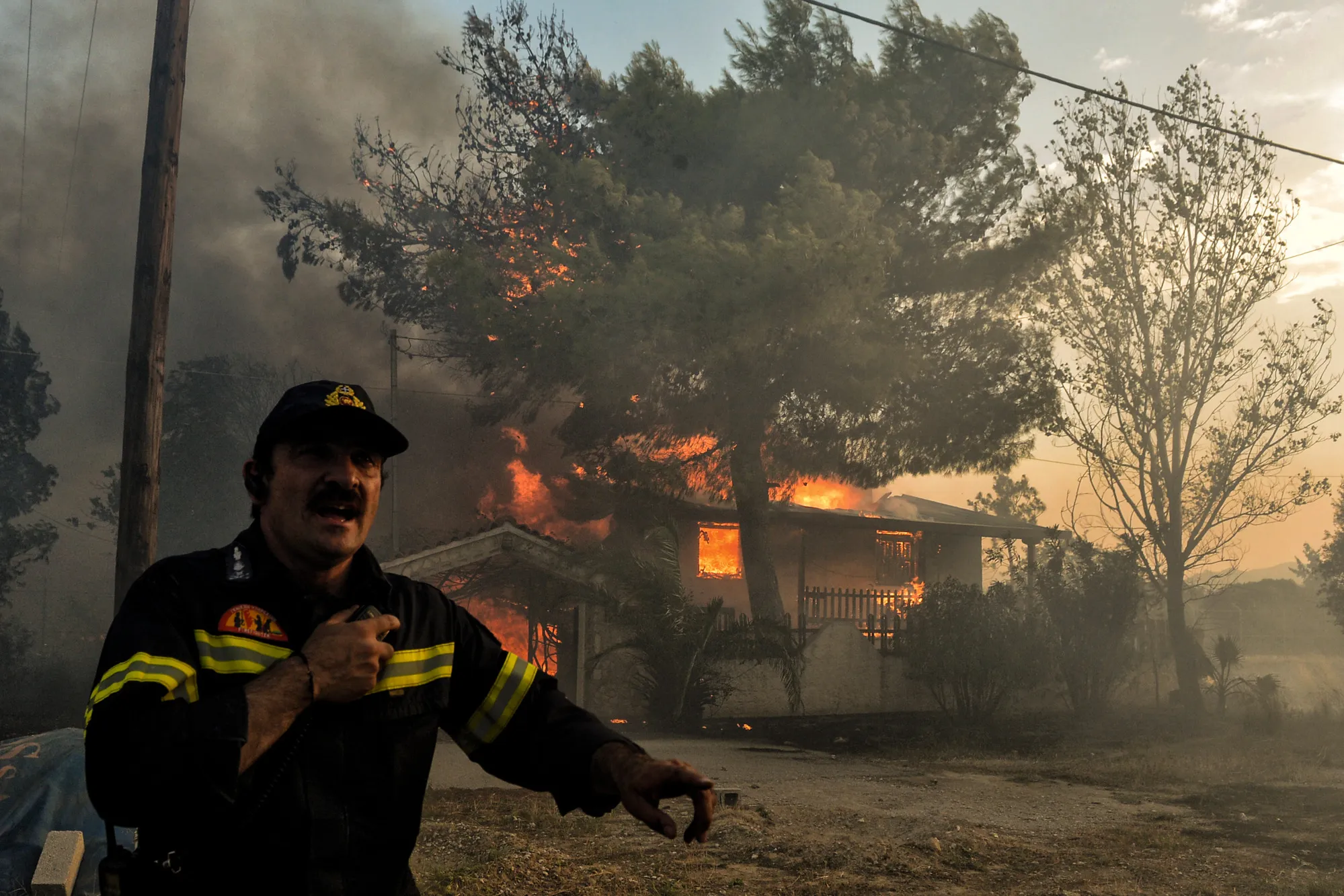 A firefighter reacts as a house burns near Athens