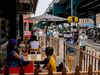 Pedestrians pass in front of customers sitting outside at a restaurant in in the Queens borough of New York.
