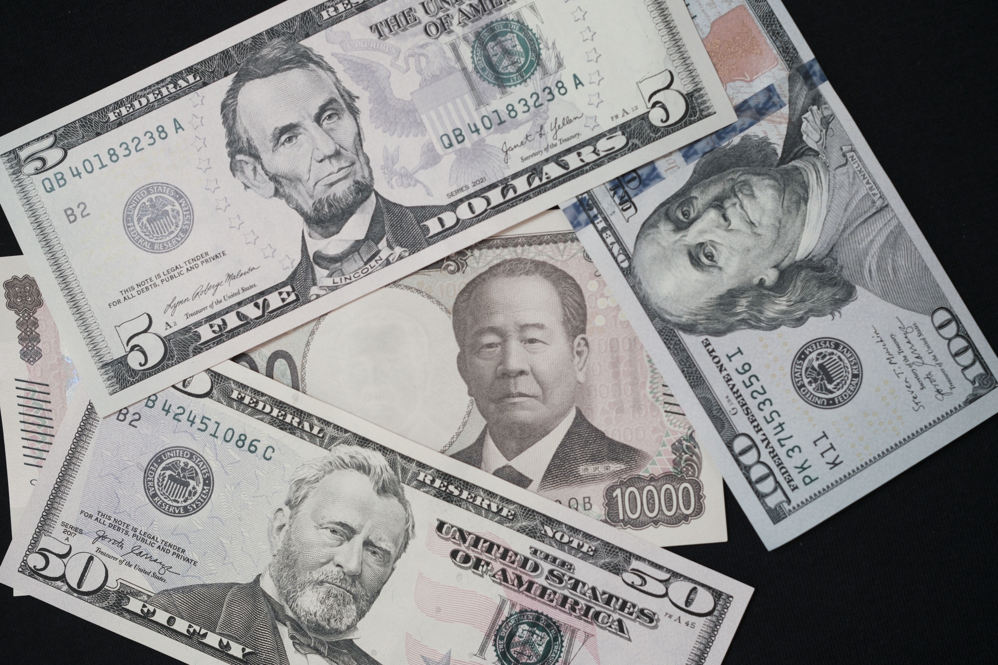 A Japanese 10,000 yen banknote with US dollar banknotes arranged for a photograph in Tokyo, Japan. 