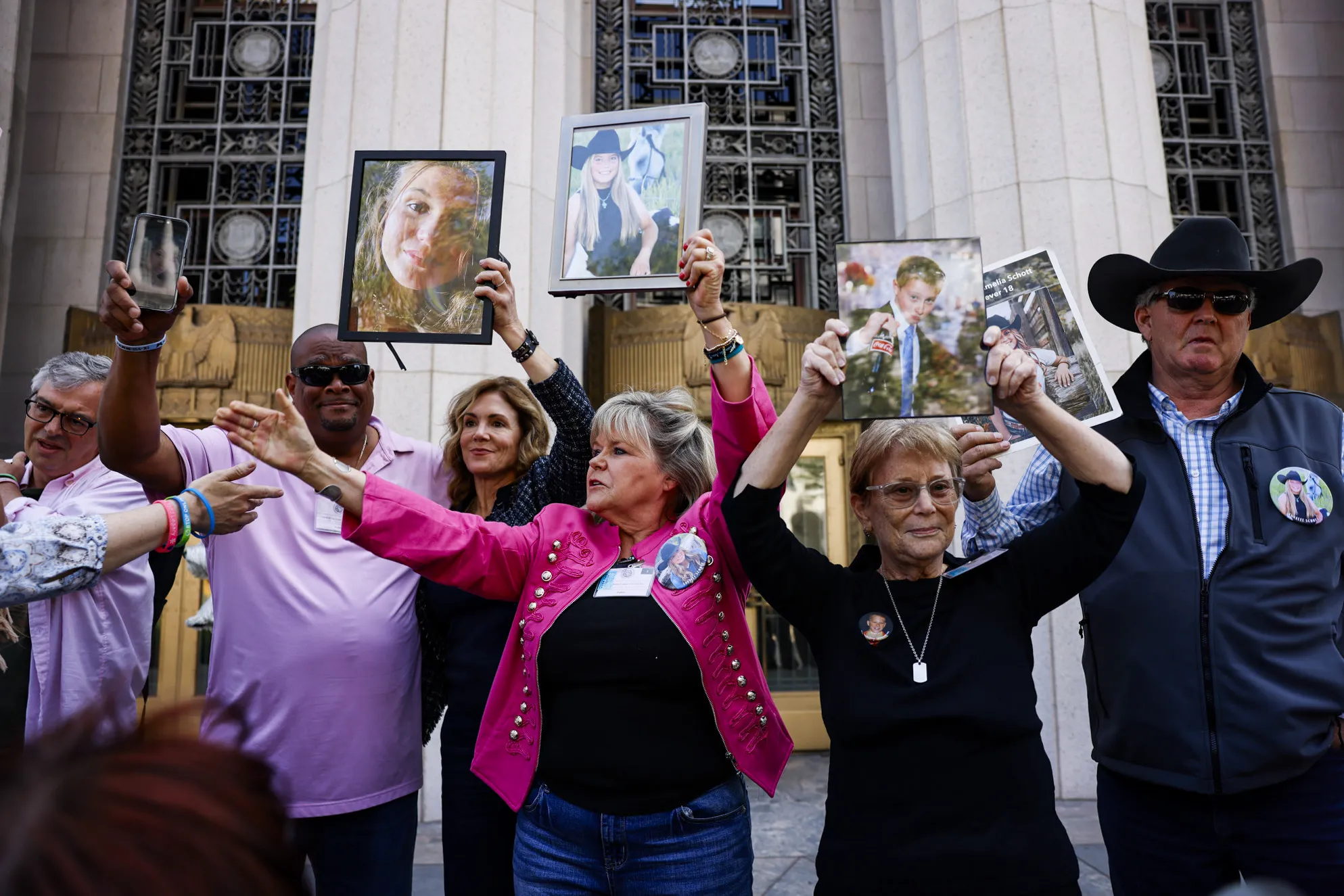 The family of victims raise photographs of their loved ones who passed away outside the Los Angeles Superior Court on March 25.