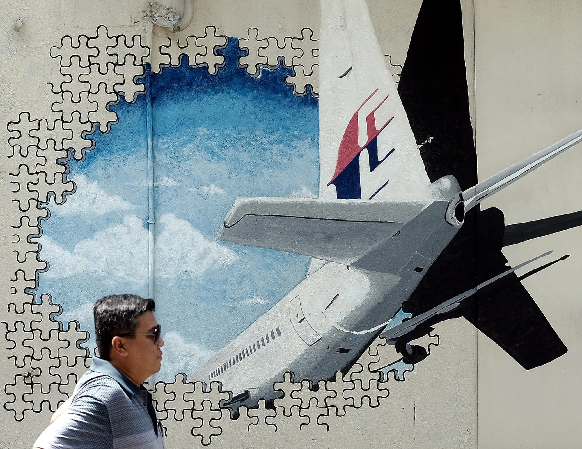 A pedestrian walks in front of a mural of missing Malaysia Airlines MH370 plane in Shah Alam.
