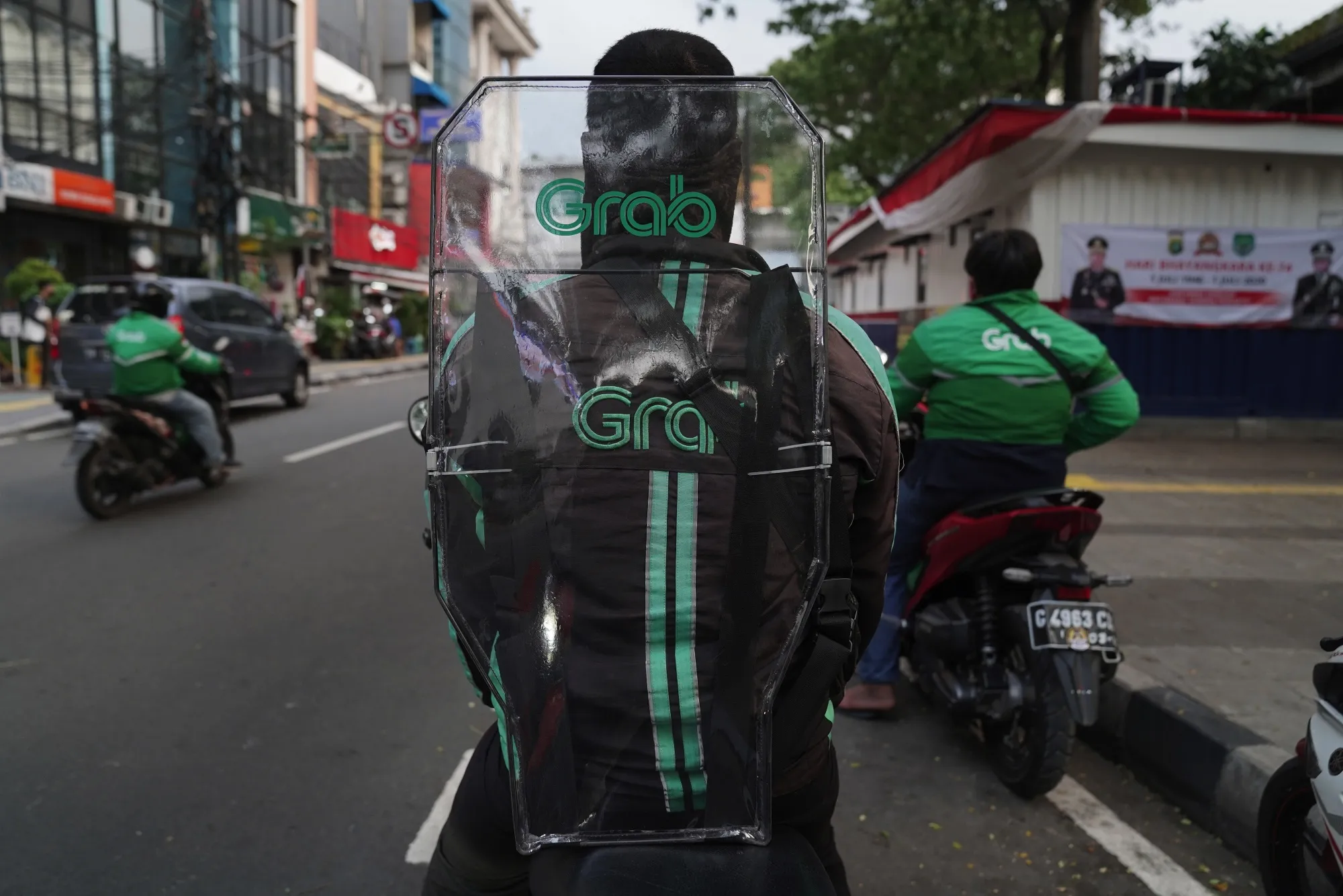 A Grab Holdings Inc. courier wears a protective shield on their back while making deliveries in Jakarta, Indonesia.