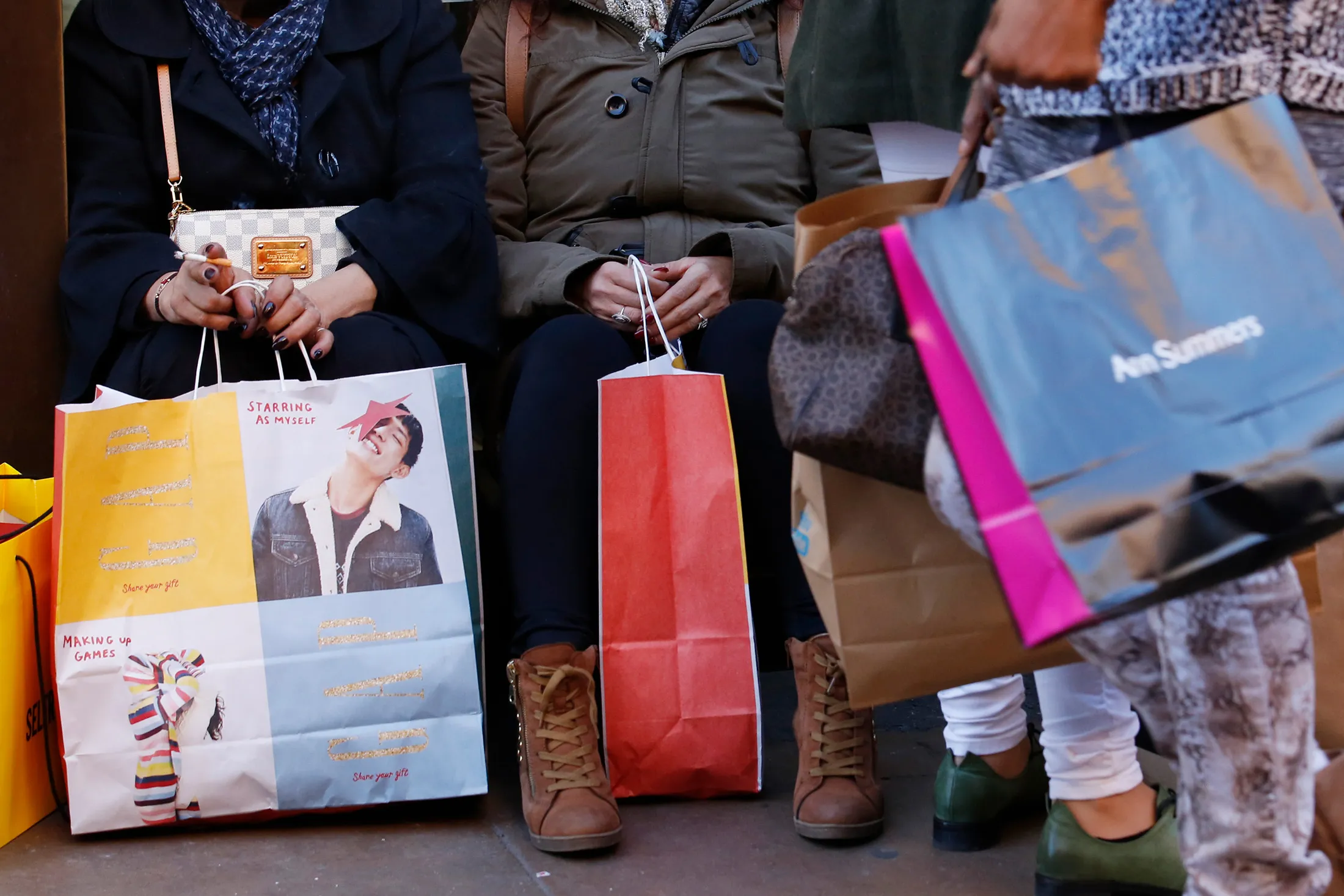 Shoppers sit and rest with multiple branded shopping bags, on Oxford Street, in London, U.K., on Friday, Nov. 25, 2016. Black Friday first became a part of U.K. shopping culture in 2014 when a rush for bargains saw fights break out as crowds gathered outside stores, in 2016 however, only 21 percent of British consumers interviewed by consultant Retail Economics said they plan to shop for Black Friday bargains.
