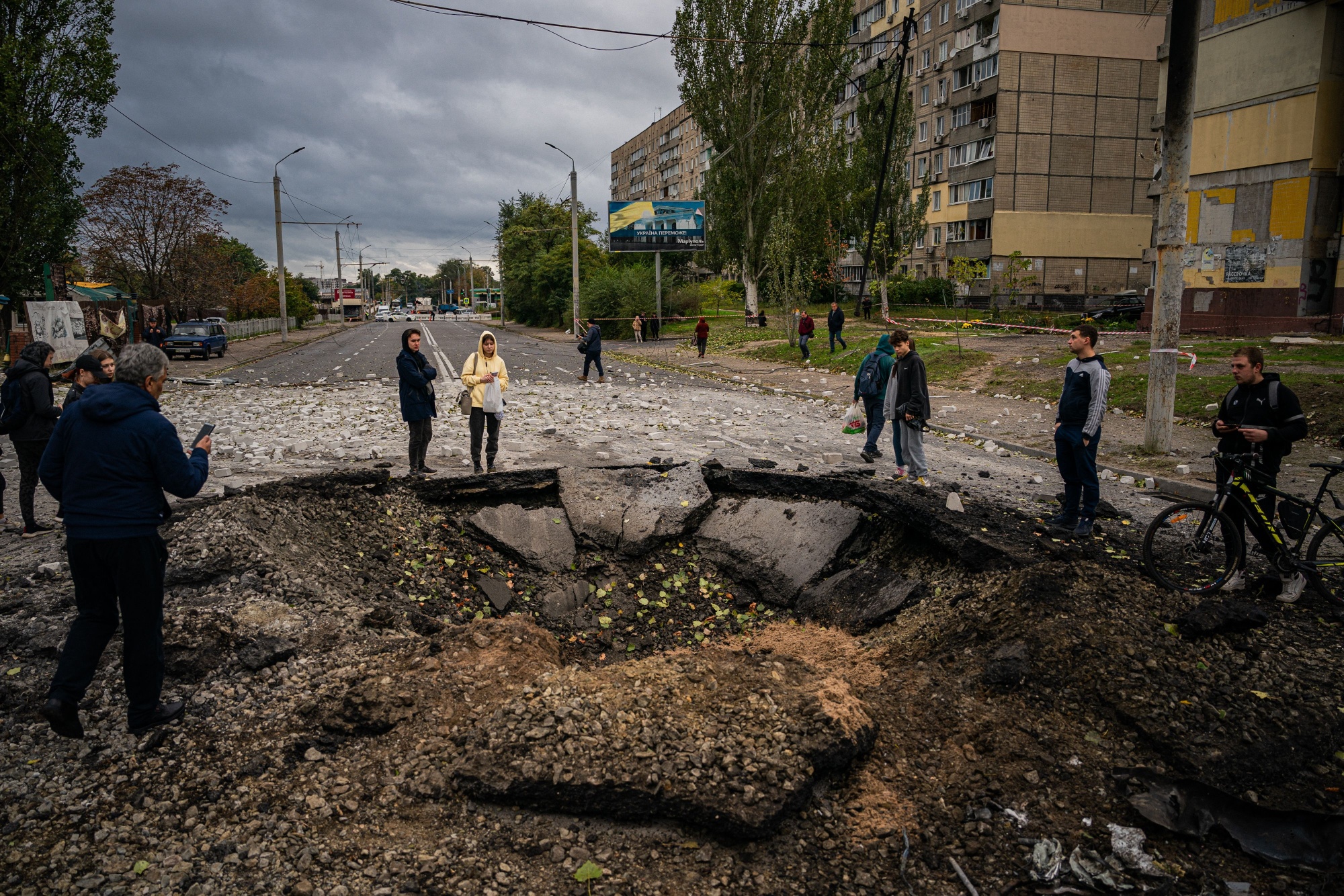 Local residents examine a crater following a missile strike in Dnipro on Oct. 10.