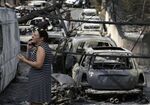 A woman stands amid the charred remains of burned-out cars in Mati, east of Athens. Wildfires have killed more than 70 people in Greece.